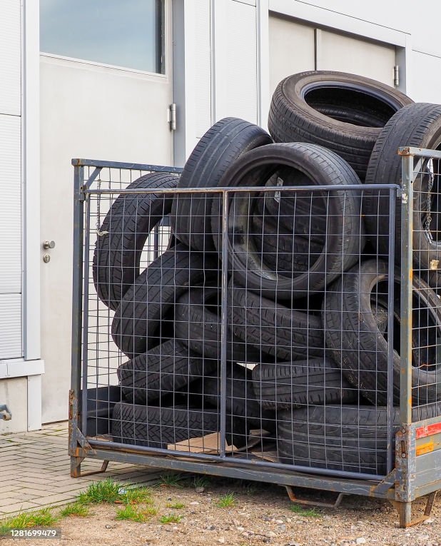 many car tires are in a metal basket in front of a car repair shop